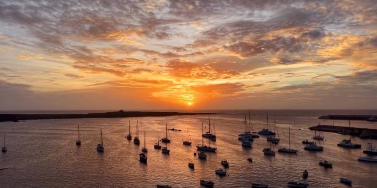 Pôr do sol dourado sobre o porto de Sal Rei com veleiros